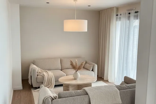 Warm minimalist living room render with a boucle sofa and travertine table