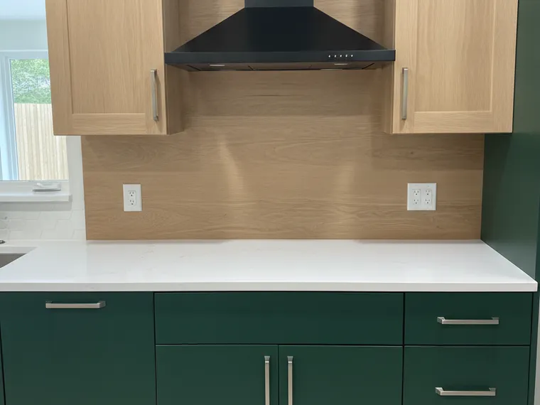 Modern kitchen idea: deep forest green lower cabinets with natural white oak upper cabinets and an oak slab backsplash