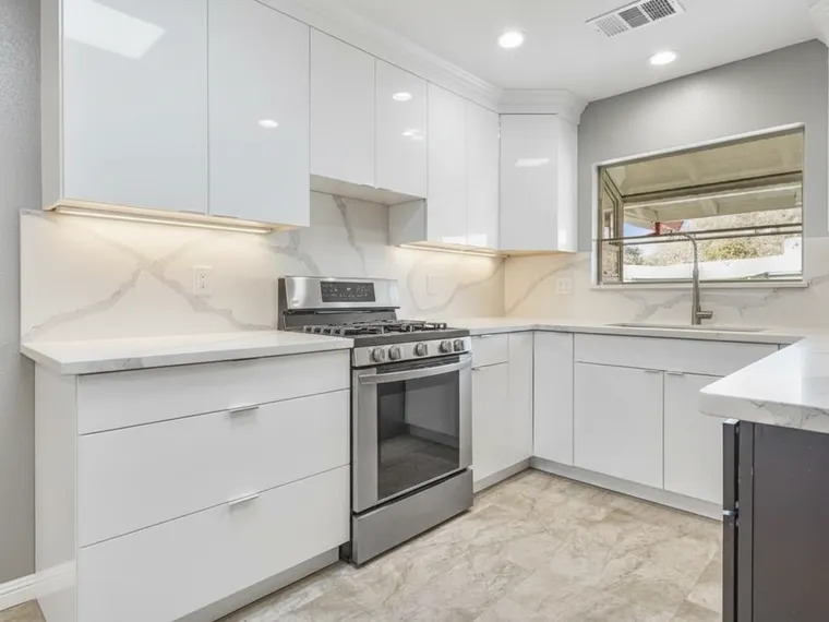 Modern kitchen idea: high-gloss white flat-front cabinets with integrated finger pulls and marble-look quartz