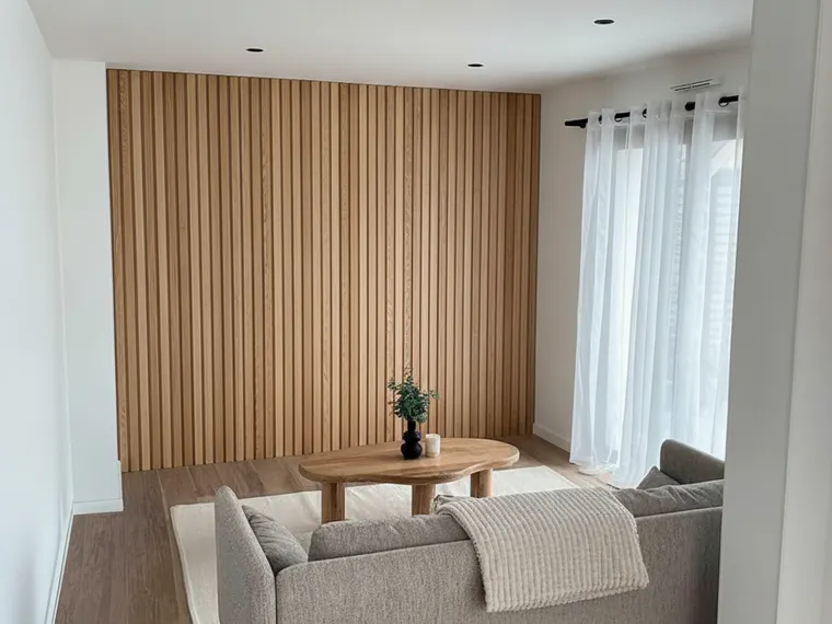 Slat wall idea: vertical natural oak wood slat panel on a living room accent wall behind a sofa
