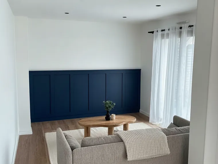 Board and batten accent wall idea: navy blue paneling on the lower two thirds of a living room wall with white above
