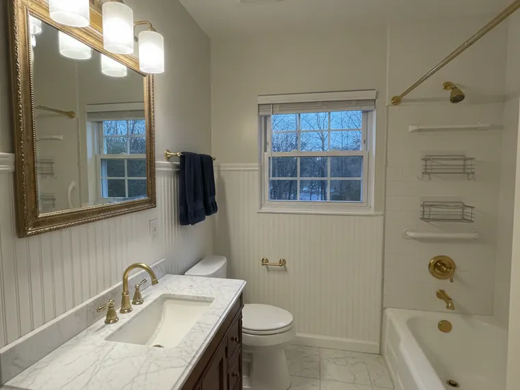 Bathroom renovation idea: white marble tile with beadboard wainscoting and brass fixtures