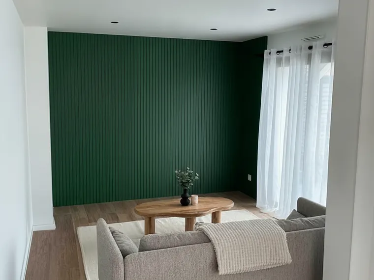 Fluted wall paneling idea: floor-to-ceiling fluted panels painted deep green on a living room accent wall