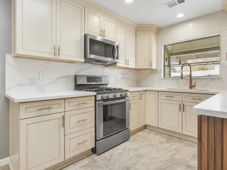 Modern kitchen idea: matte cream flat-panel cabinets with a fluted walnut island and brushed brass hardware