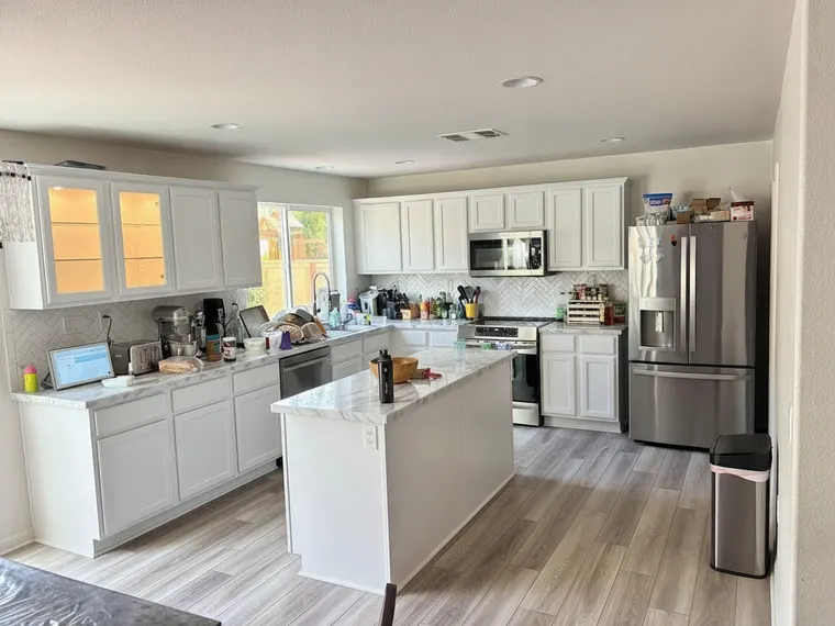 Corner cabinet idea in a white kitchen: end-of-run upper cabinet replaced with a lit glass-front display cabinet