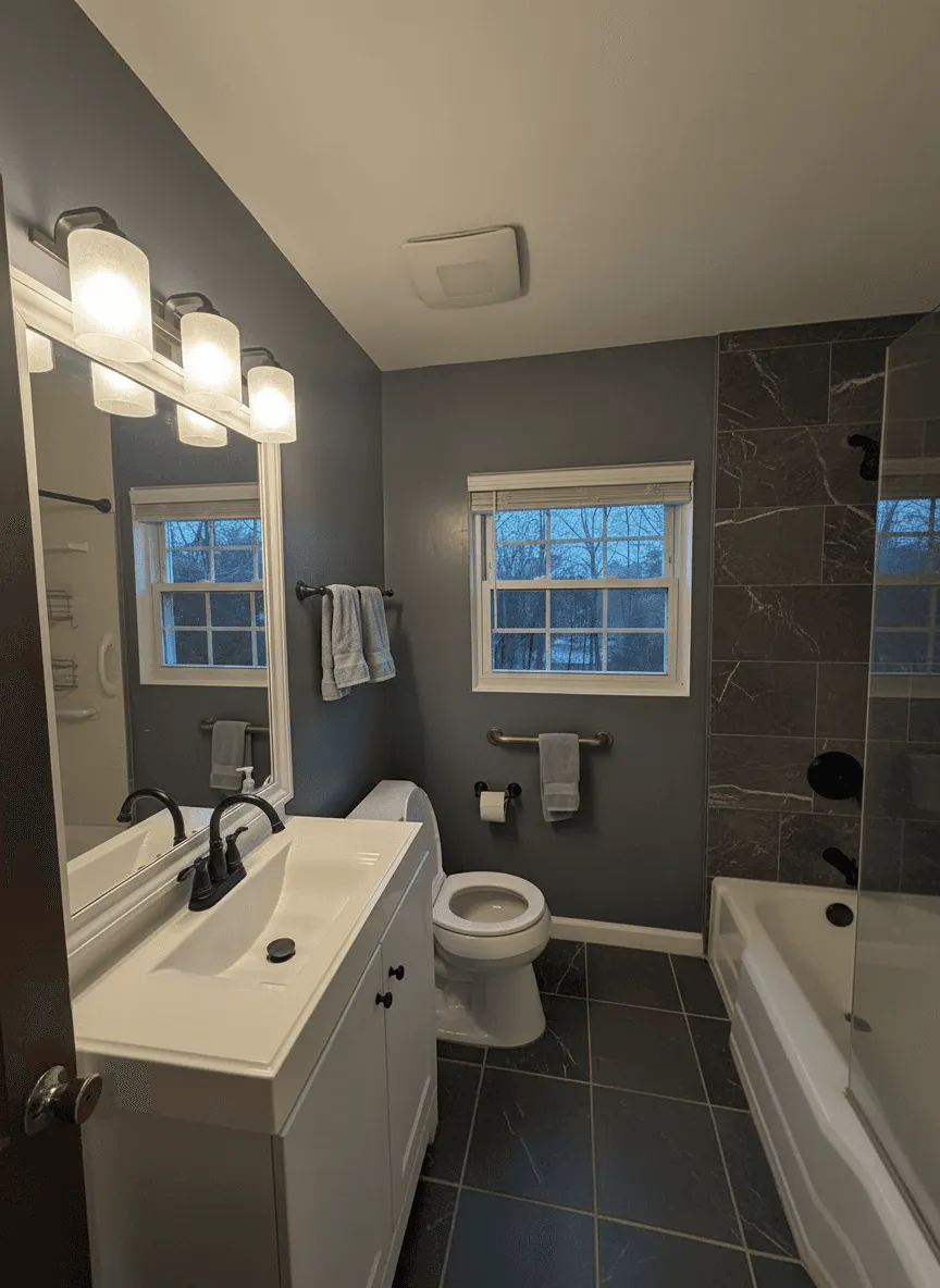 Same bathroom transformed with deep charcoal walls, dark marble tub surround, and slate floors