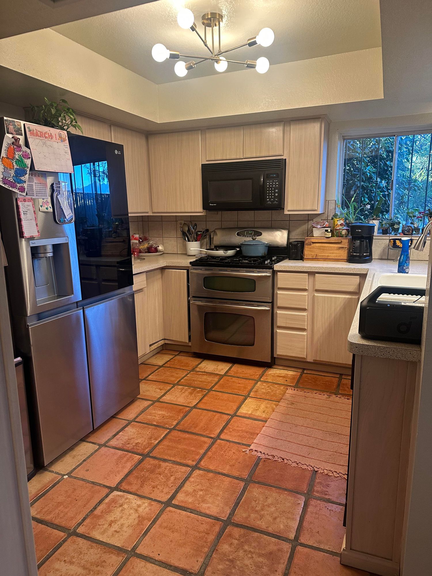 The original kitchen — faded pink cabinets, Saltillo terracotta tile, sputnik chandelier
