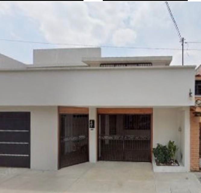 The original flat-white house with two iron gates, garage door, flat roof, raised parapet